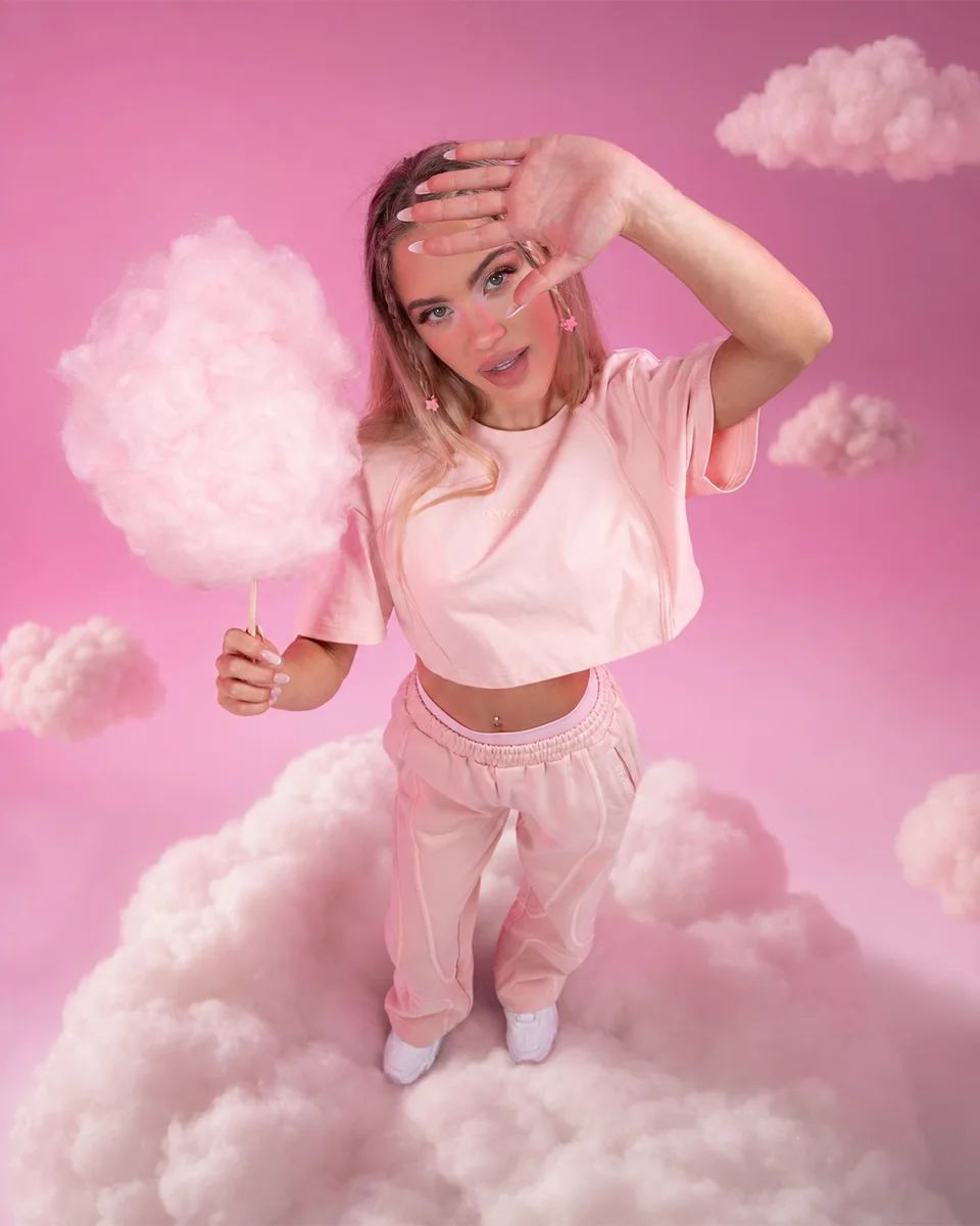 GymBeam-Model in einem rosa Outfit zwischen Wolken