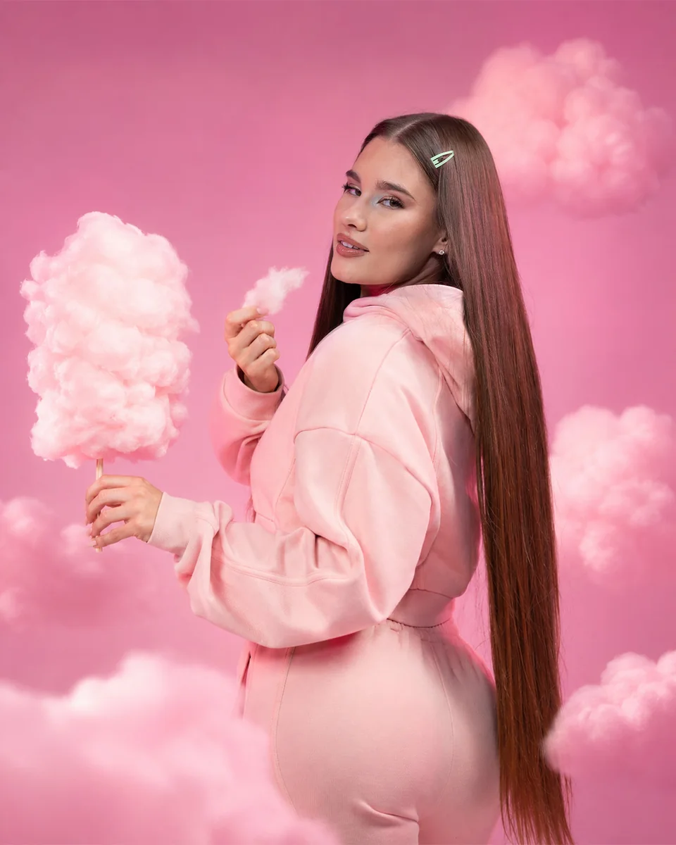 GymBeam-Model in einem rosa Outfit mit Zuckerwatte zwischen Wolken