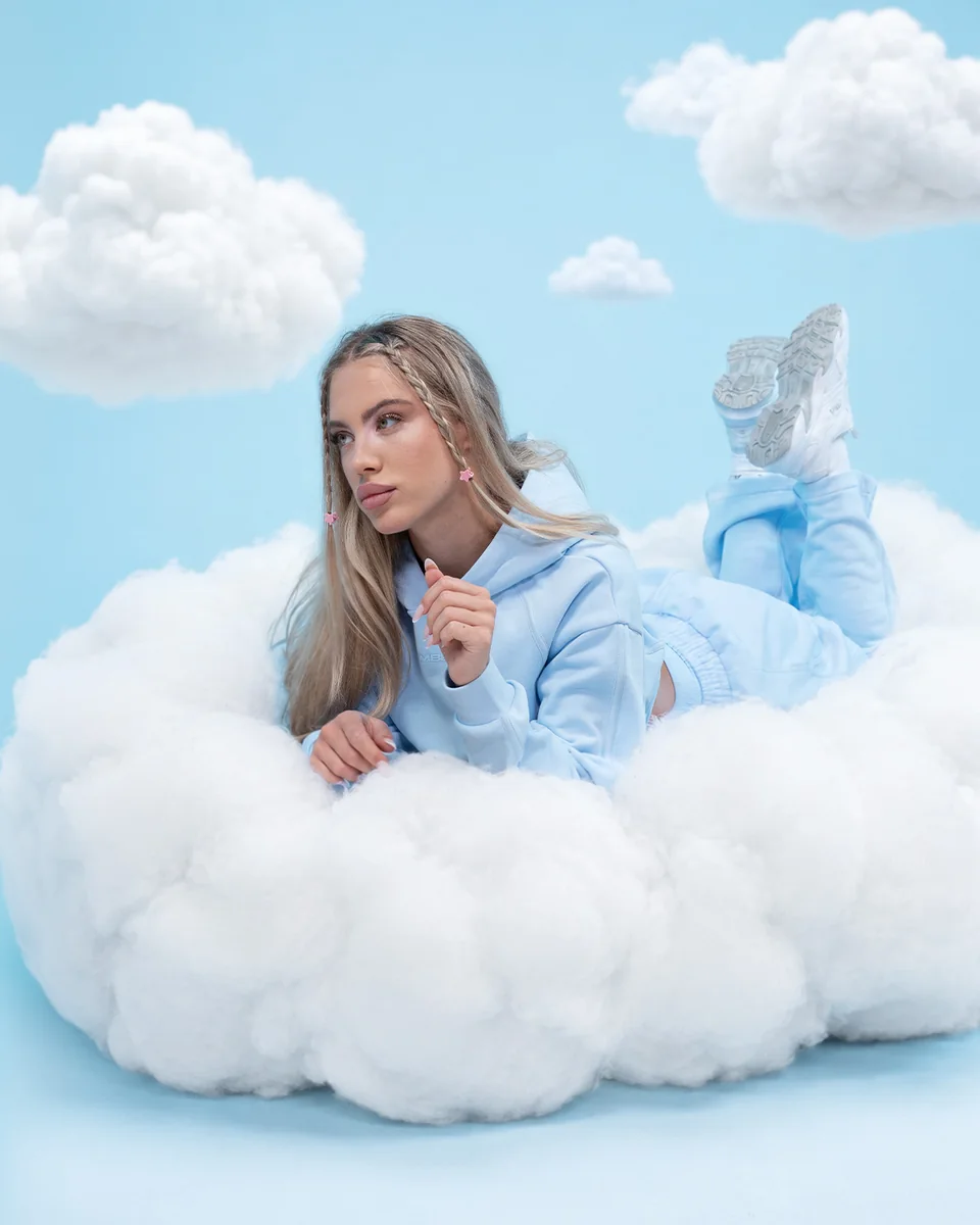 GymBeam-Model in einem blauen Outfit auf einer Wolke