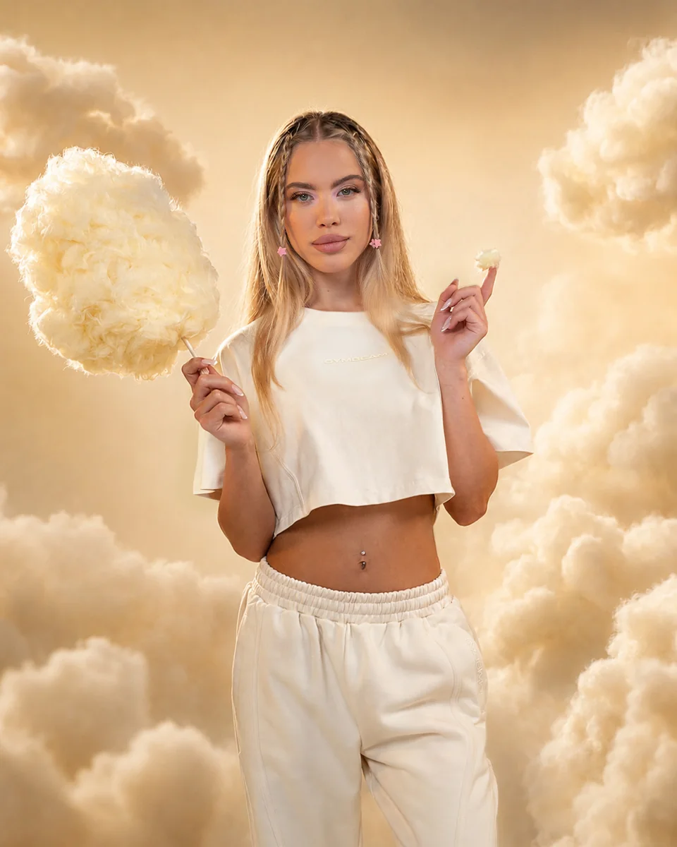 Cremefarbenes GymBeam-Outfit und Zuckerwatte am goldenen Himmel