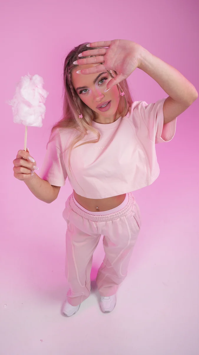 Vor der Postproduktion: ursprüngliche Studioaufnahme eines Models mit Zuckerwatte vor rosa Hintergrund