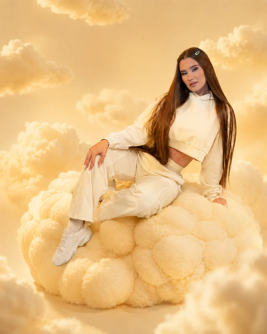 GymBeam-Model in einem cremefarbenen Outfit zwischen goldenen Wolken