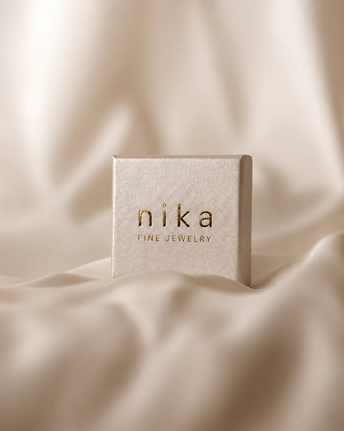 Nika Fine Jewelry — Goldprägung des Logos auf heller Verpackung